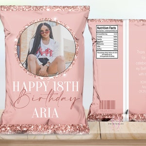 Puede incluir: Bolsa de patatas fritas rosa con detalles de purpurina oro rosa. La parte delantera presenta una foto dentro de un c&iacute;rculo, con el texto "HAPPY 18TH BIRTHDAY ARIA". La parte trasera incluye una tabla de informaci&oacute;n nutricional y un mensaje de agradecimiento.