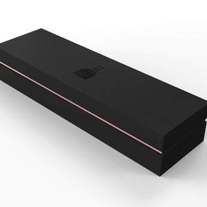 May include: A black rectangular box with a thin rose gold line around the edge. The box has a small logo on the top.
