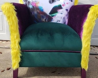 May include: A green velvet armchair with yellow faux fur trim and a colorful abstract print on the back. The chair has purple velvet accents and wooden legs.