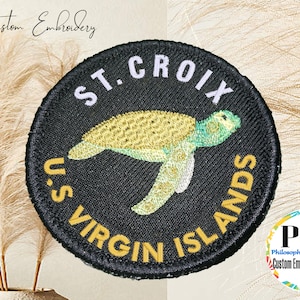 May include: A black embroidered patch featuring a yellow and green sea turtle, surrounded by the text "ST. CROIX U.S. VIRGIN ISLANDS".