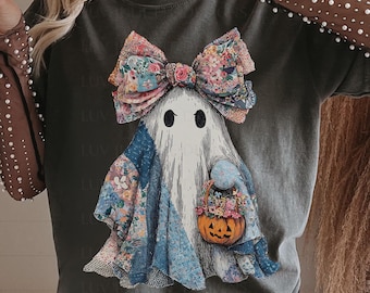 May include: Dark gray t-shirt featuring a whimsical ghost design. The ghost wears a floral bow and patchwork clothing, holding a pumpkin basket. The design has a vintage, slightly distressed look, perfect for Halloween.