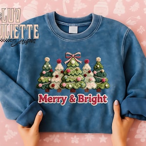 Puede incluir: Una sudadera azul con un diseño bordado de cinco árboles de Navidad, cada uno decorado con adornos y rematado con un pompón. El texto "Merry & Bright" está debajo de los árboles. La marca "Luv Juliette Designs" está en la esquina superior izquierda.