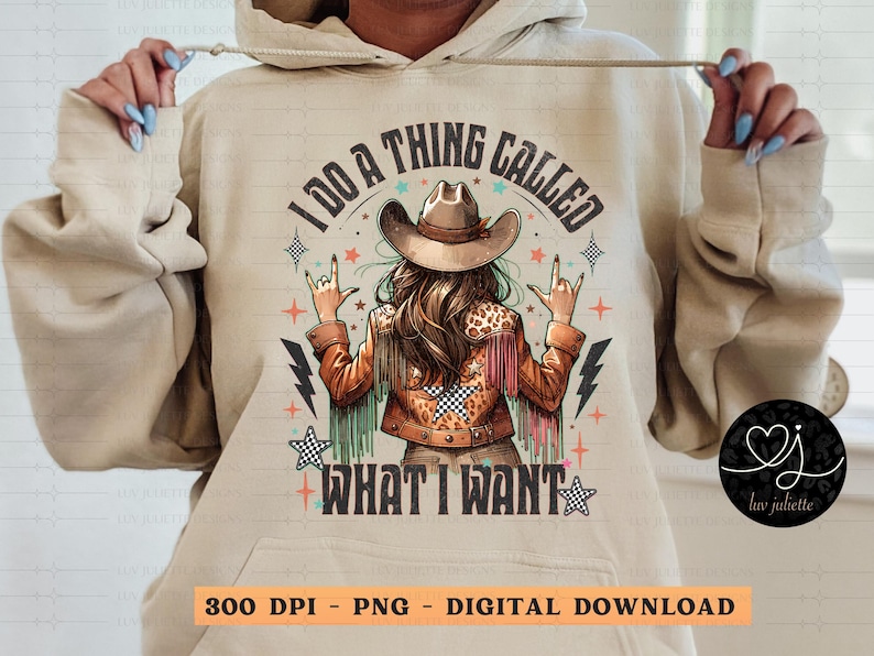 May include: Beige hoodie with a graphic of a woman in a cowboy hat and jacket, with the text "I DO A THING CALLED WHAT I WANT". The design includes stars, lightning bolts, and a heart logo.