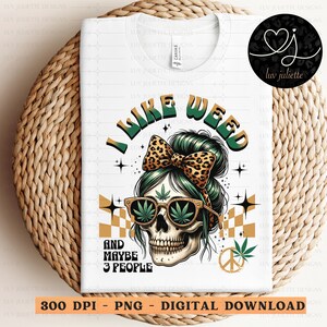 Könnte beinhalten: Ein weißes T-Shirt mit einem grünen, schwarzen und gelben Totenkopf-Motiv. Der Totenkopf trägt ein grünes Stirnband mit einer Schleife im Leopardenmuster. Der Text "I Like Weed" befindet sich über dem Totenkopf und der Text "And Maybe 3 People" unter dem Totenkopf.
