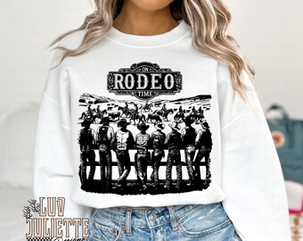 以下が含まれることがあります： 黒いバナーに「On Rodeo Time」の文字が書かれた、馬に乗ったカウボーイの黒いグラフィックが描かれた白いスウェットシャツです。