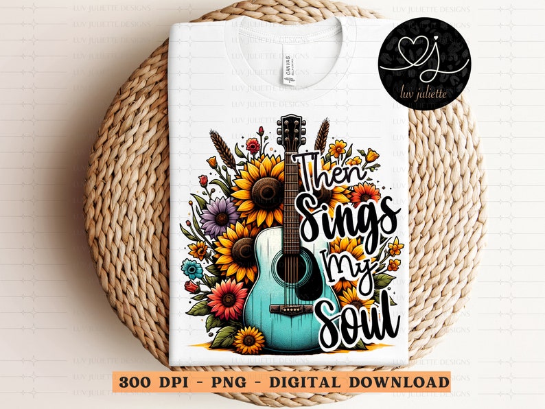 Pu&ograve; includere: Una maglietta bianca con una chitarra acustica blu e verde circondata da fiori colorati. Il testo "Then Sings My Soul" &egrave; scritto in lettere nere.