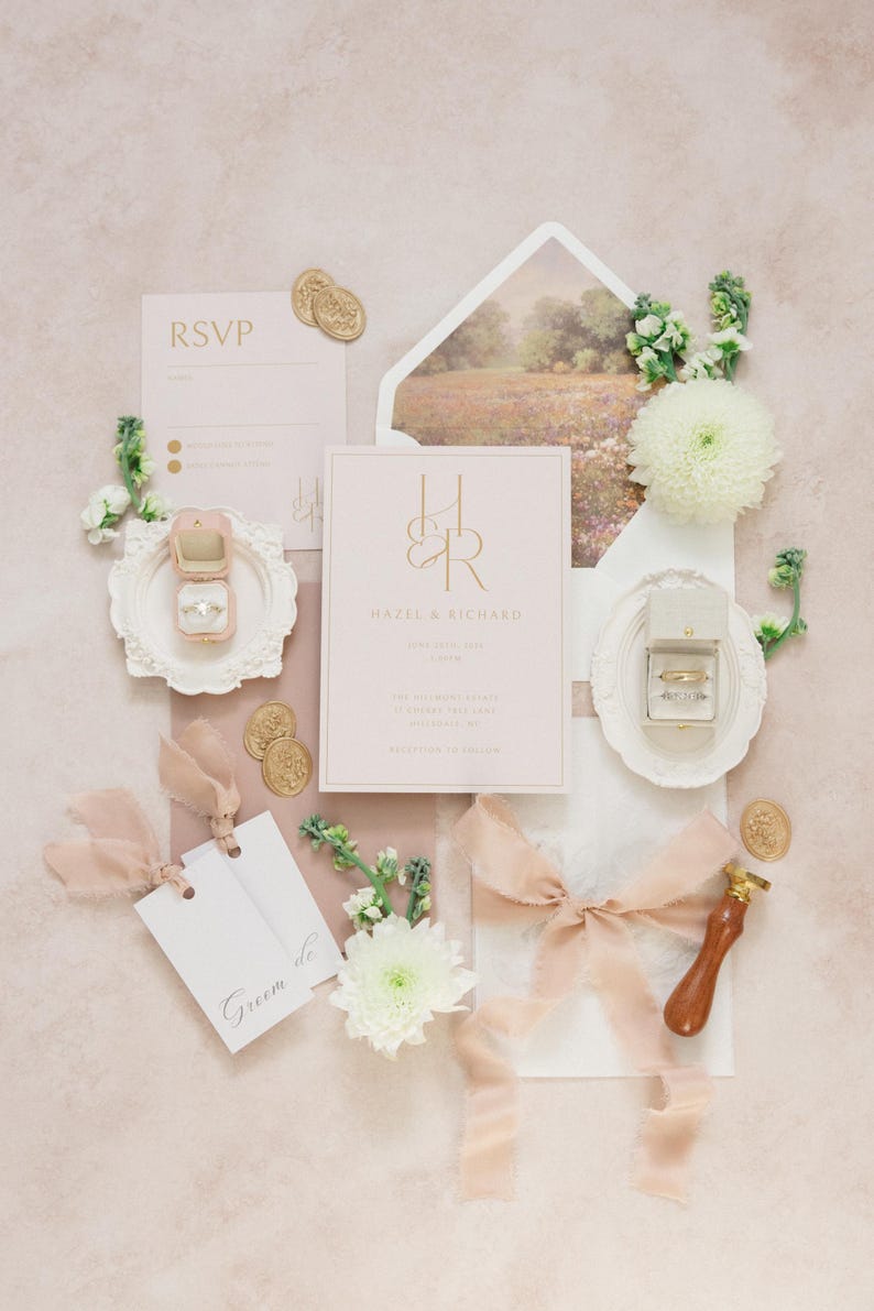 Puede incluir: Un conjunto de invitaciones de boda en tonos rosa rubor y dorado. El conjunto incluye una invitaci&oacute;n, una tarjeta de confirmaci&oacute;n de asistencia y etiquetas, junto con un joyero, sellos de cera y detalles florales. La invitaci&oacute;n muestra los nombres "Hazel & Richard".