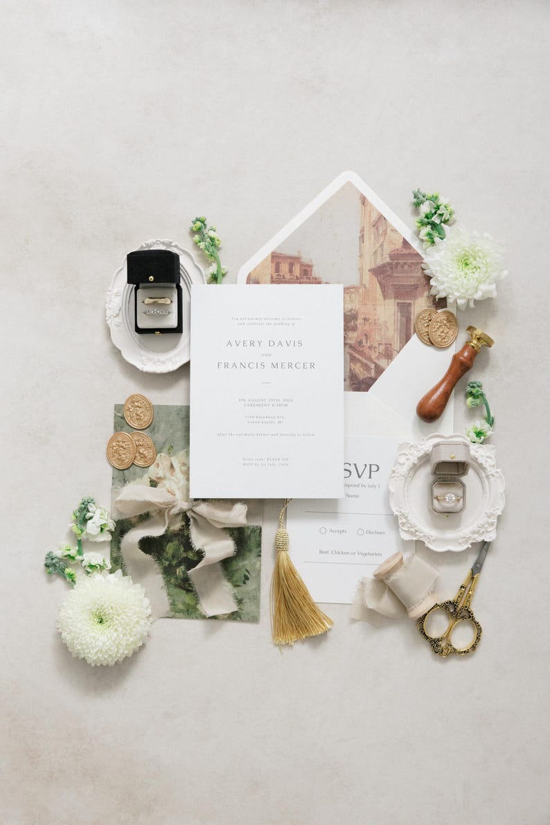 Puede incluir: Conjunto de invitaciones de boda con una tarjeta de invitaci&oacute;n central con los nombres "Avery Davis" y "Francis Mercer". El conjunto incluye anillos en cajas, detalles florales, borla dorada, sellos de cera y tijeras decorativas.