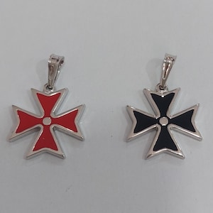 Könnte beinhalten: Zwei silberne Anhänger mit einem Malteserkreuz-Design. Ein Kreuz ist rot, das andere schwarz, beide mit silbernen Rändern und einer kleinen Schlaufe für eine Kette. Auf weißem Hintergrund.