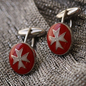 May include: A pair of silver cufflinks with red and white enamel Maltese crosses.