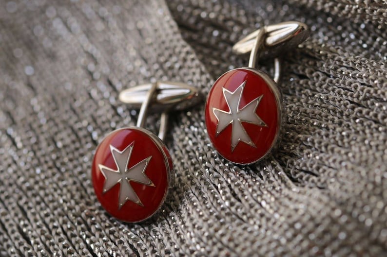 May include: A pair of silver cufflinks with red and white enamel Maltese crosses.