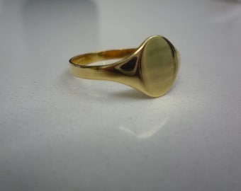 May include: A gold signet ring with a smooth, oval-shaped top.