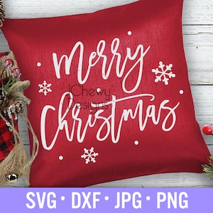 May include: Red cushion with white text that says "Merry Christmas" with snowflakes on a white wooden background.