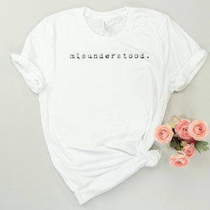 May include: White t-shirt with the text "misunderstood." printed in black on the front.