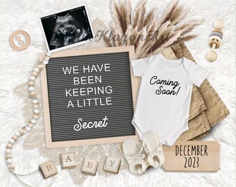 May include: A pregnancy announcement with a letter board that reads "We have been keeping a little secret". There is a white onesie with the text "Coming Soon!" and a sonogram image. The announcement also includes wooden blocks that spell out "baby" and a sign that says "December 2023".