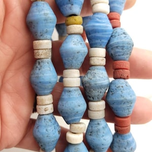 May include: A strand of blue, white, and red glass beads. The blue beads are swirled and have a speckled texture. The white beads are round and the red beads are cylindrical.