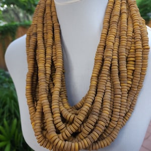 Peut inclure: Un long collier multi-rangs composé de petites perles rondes brun-jaune. Le collier est drapé sur le cou d'un mannequin blanc.