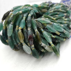 May include: A strand of green, blue, and brown glass beads. The beads are irregular in shape and have a frosted finish.