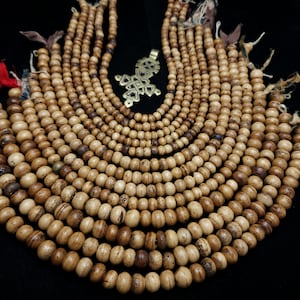 May include: A collection of brown wooden bead necklaces, each strand is made of round beads with a natural wood finish. The necklaces are arranged in a circular pattern, creating a visually appealing display.