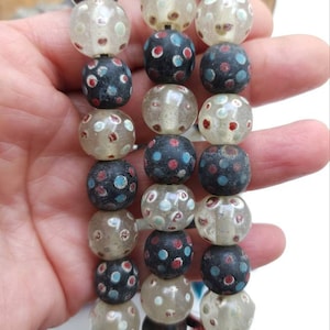 以下が含まれることがあります： 白、赤、青のドット模様の黒いガラスビーズのネックレス。ビーズは半透明で光沢のある仕上げです。