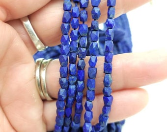 May include: A strand of dark blue faceted lapis lazuli beads. The beads are small and have a slightly irregular shape.