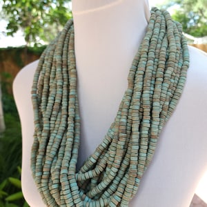 Pode incluir: Um colar de várias voltas azul turquesa feito de contas redondas de madeira. O colar é em camadas e tem um visual rústico e terroso.
