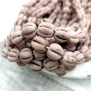 以下が含まれることがあります： リブ模様の淡いピンク色のガラスビーズのストランド。ビーズは楕円形で、わずかにフロスト加工が施されています。