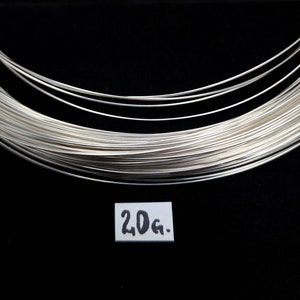 Può includere: Un rotolo di filo d'argento da 20 grammi su uno sfondo nero.