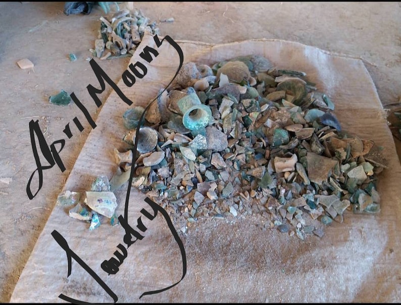 May include: A burlap sack filled with a large pile of broken glass and pottery shards. The shards are various shades of green, brown, and white. The text "April Moon" and "Laundry" is written in black marker on the sack.