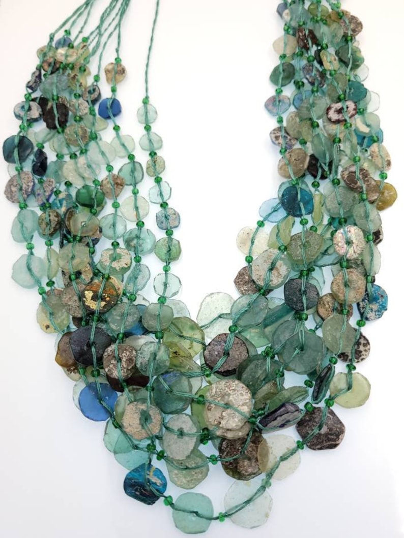 May include: A multi-strand necklace made of green, blue, and brown glass beads. The beads are various sizes and shapes, and some have a frosted or iridescent finish.