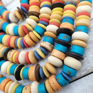 May include: A strand of colorful wooden beads with turquoise accents. The beads are arranged in a repeating pattern of yellow, orange, red, blue, and white.