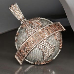 May include: A gold and diamond pendant featuring a globe with the words "THE WORLD IS YOURS" encircling it.