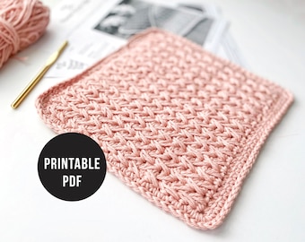 May include: A square, light pink crocheted item with a textured weave pattern. A gold crochet hook and a ball of matching yarn are in the background. A black circle with the words "PRINTABLE PDF" is in the lower left corner.