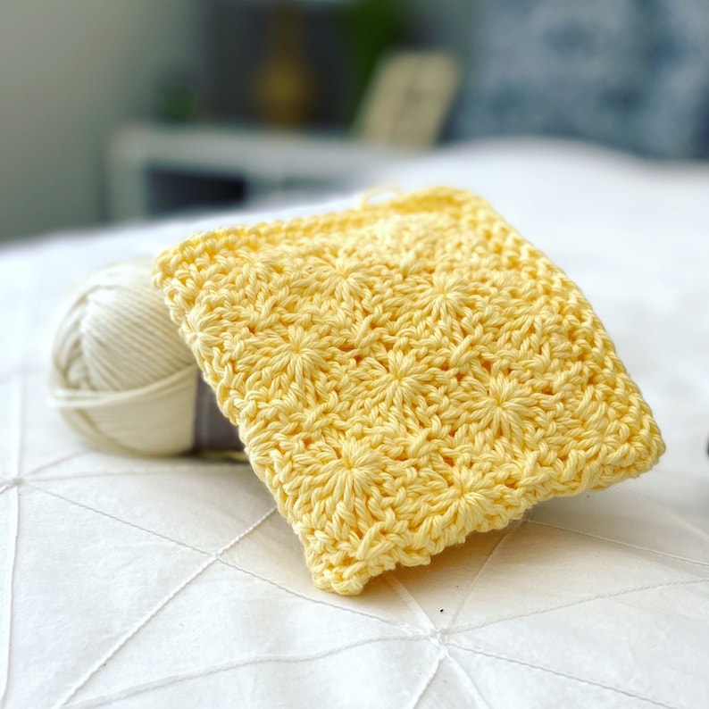 May include: A yellow crocheted square dishcloth with a starburst pattern.