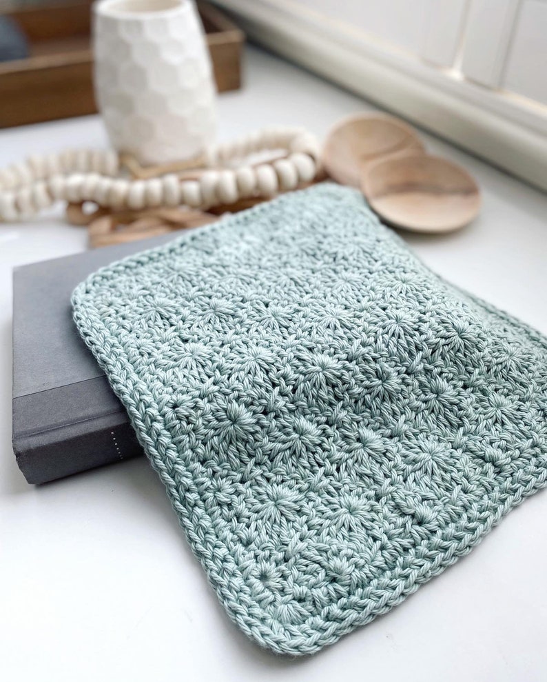 May include: A light blue crocheted dishcloth with a textured pattern.