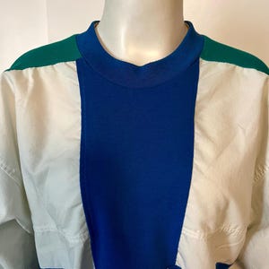 May include: A color-blocked sweatshirt in white, blue, and green. The top features a ribbed blue center panel, white side panels, and green shoulder accents. The lower portion of the shirt has a "PRO CLUB" logo.