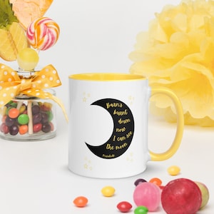 May include: White ceramic mug with a yellow rim and handle. The mug features a black crescent moon with gold stars and text that reads "Barn's burnt down now I can see the moon" with the word "remarkable" in smaller font below the text.