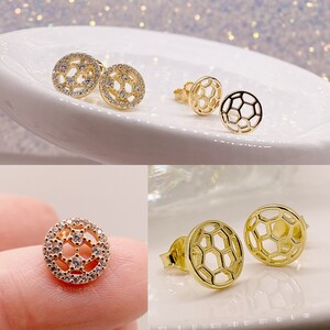 Peut inclure: Deux paires de boucles d'oreilles dor&eacute;es avec un motif de ballon de football. Une paire pr&eacute;sente un ballon de football avec des pierres de zircone cubique transparentes, tandis que l'autre paire pr&eacute;sente un motif de ballon de football creux.