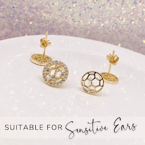 Peut inclure: Une paire de boucles d'oreilles clous dor&eacute;es avec un motif de ballon de football. Une boucle d'oreille est sertie de pierres de zircone cubique transparentes. Les boucles d'oreilles conviennent aux oreilles sensibles.