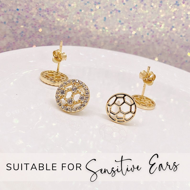 Peut inclure: Une paire de boucles d'oreilles clous dor&eacute;es avec un motif de ballon de football. Une boucle d'oreille est sertie de pierres de zircone cubique transparentes. Les boucles d'oreilles conviennent aux oreilles sensibles.