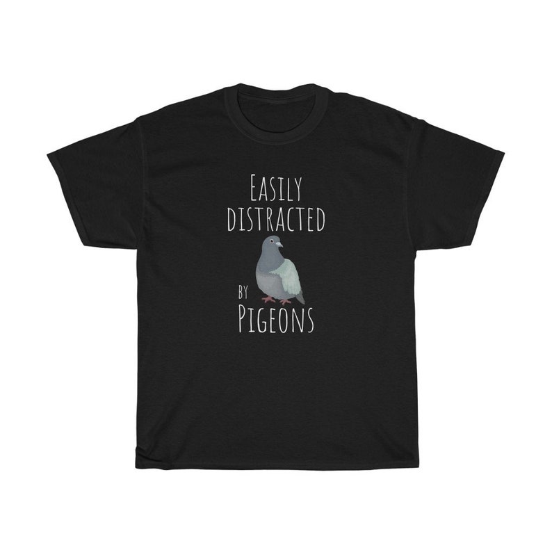 May include: Black t-shirt with white text that reads "Easily Distracted by Pigeons". A cartoon pigeon is pictured below the text.