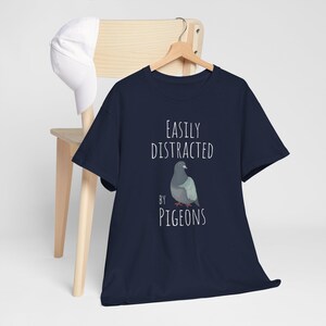 May include: A navy blue t-shirt with the text "Easily Distracted by Pigeons" and a cartoon pigeon illustration.