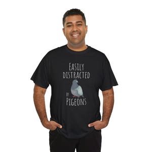 May include: A black t-shirt with the text "Easily Distracted by Pigeons" and a cartoon image of a pigeon.