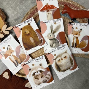 Könnte beinhalten: Sechs Bügelbilder mit Waldtieren, darunter ein Fuchs, eine Eule, ein Waschbär, ein Bär, ein Kaninchen und ein Pilz. Jedes Bügelbild hat einen weißen Hintergrund mit braunem Text, der "Schneck Bert Bügelbild" lautet.