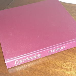May include: A burgundy hardcover book titled "Entertaining" by Stewart, with a gold-colored design on the front cover.