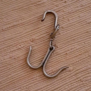 May include: A silver metal hook with three prongs. The hook is designed for hanging items.