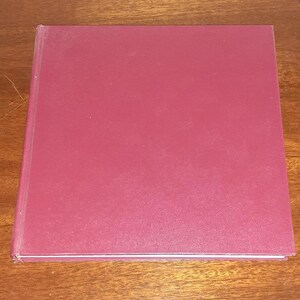 May include: A burgundy hardcover book with a smooth, textured cover.