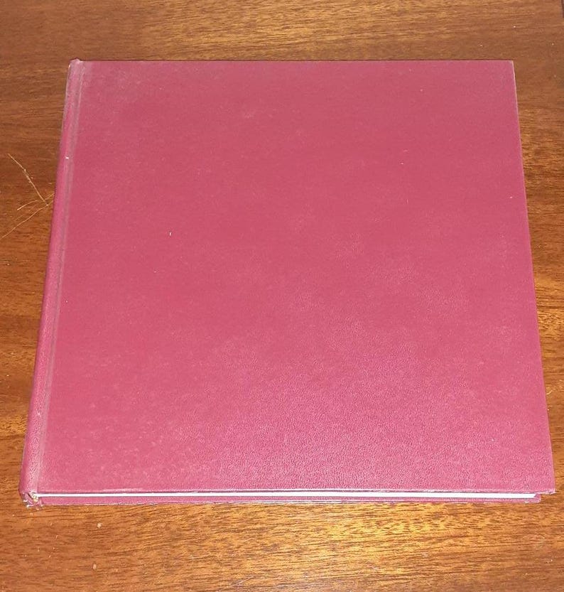 May include: A burgundy hardcover book with a smooth, textured cover.