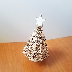 Puede incluir: Un árbol de Navidad de madera hecho de formas de copo de nieve que se entrelazan. El árbol está decorado con una estrella blanca en la parte superior.
