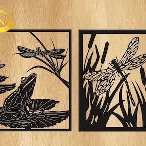 Pode incluir: Duas peças de arte de parede com moldura preta. Uma apresenta um sapo numa folha de nenúfar com uma libélula. A outra mostra uma libélula entre juncos. O fundo é um grão de madeira clara.